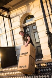 Removals team member loading large moving boxes into a property in Brighton during a house move