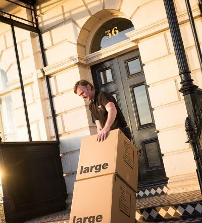 Removals team member loading large moving boxes into a property in Brighton during a house move